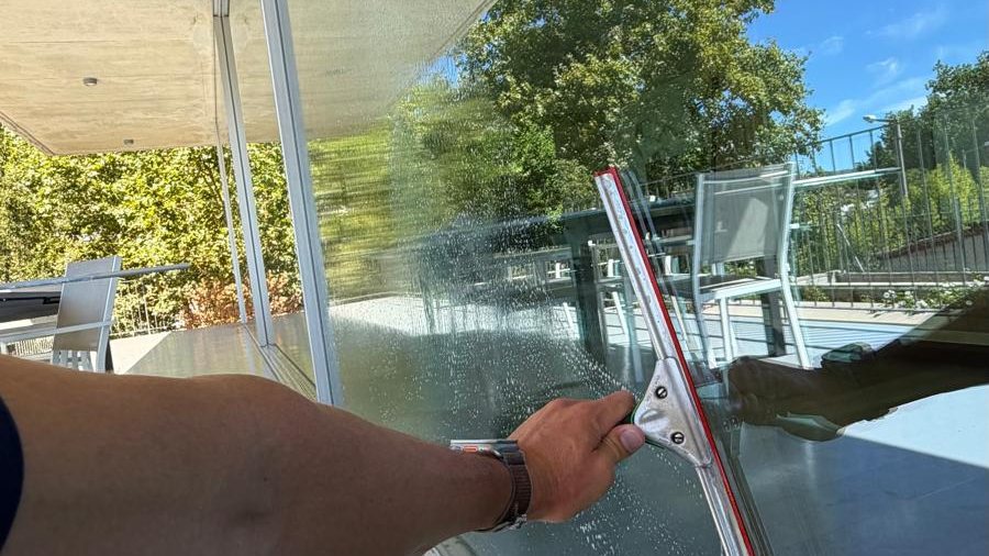 Técnico a passar o rodo num pano de vidro de grande formato